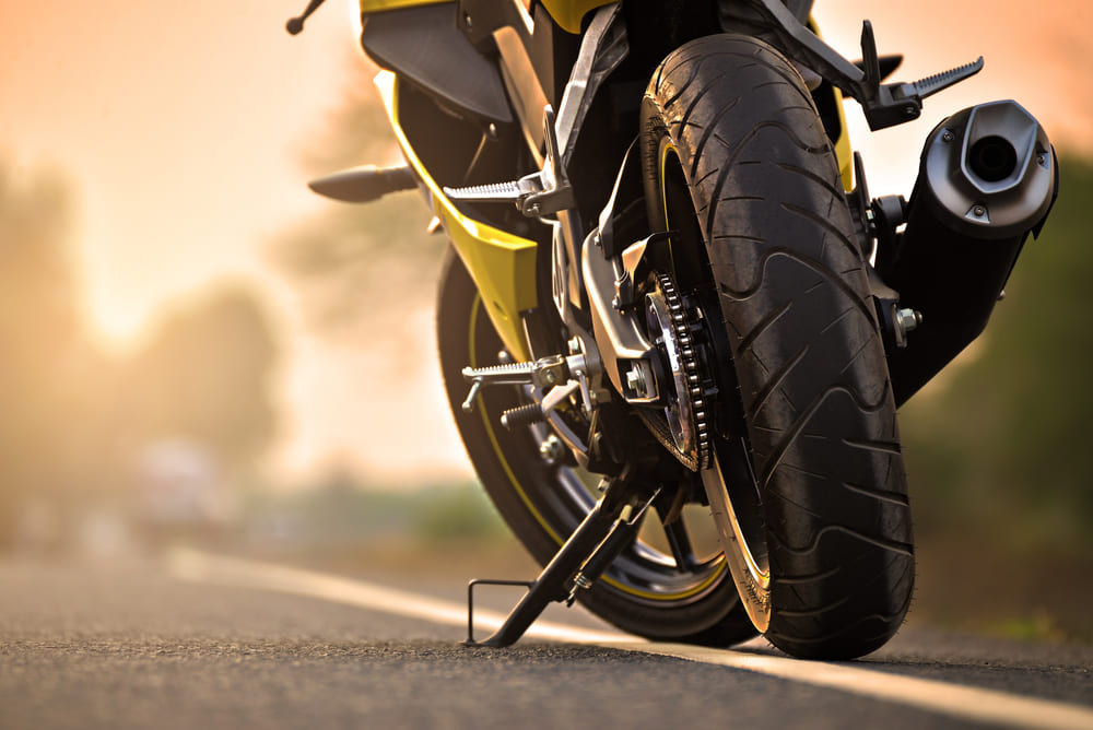 motorka na stojanu na kraji silnice v západu slunce, detail na zadní kolo